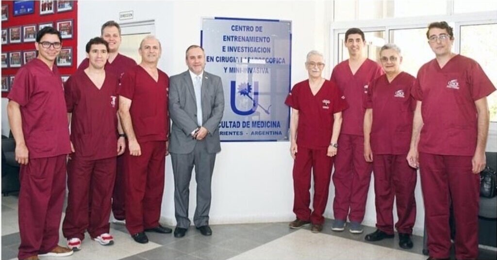 Equipo de cirugía junto a cartelería de la facultad